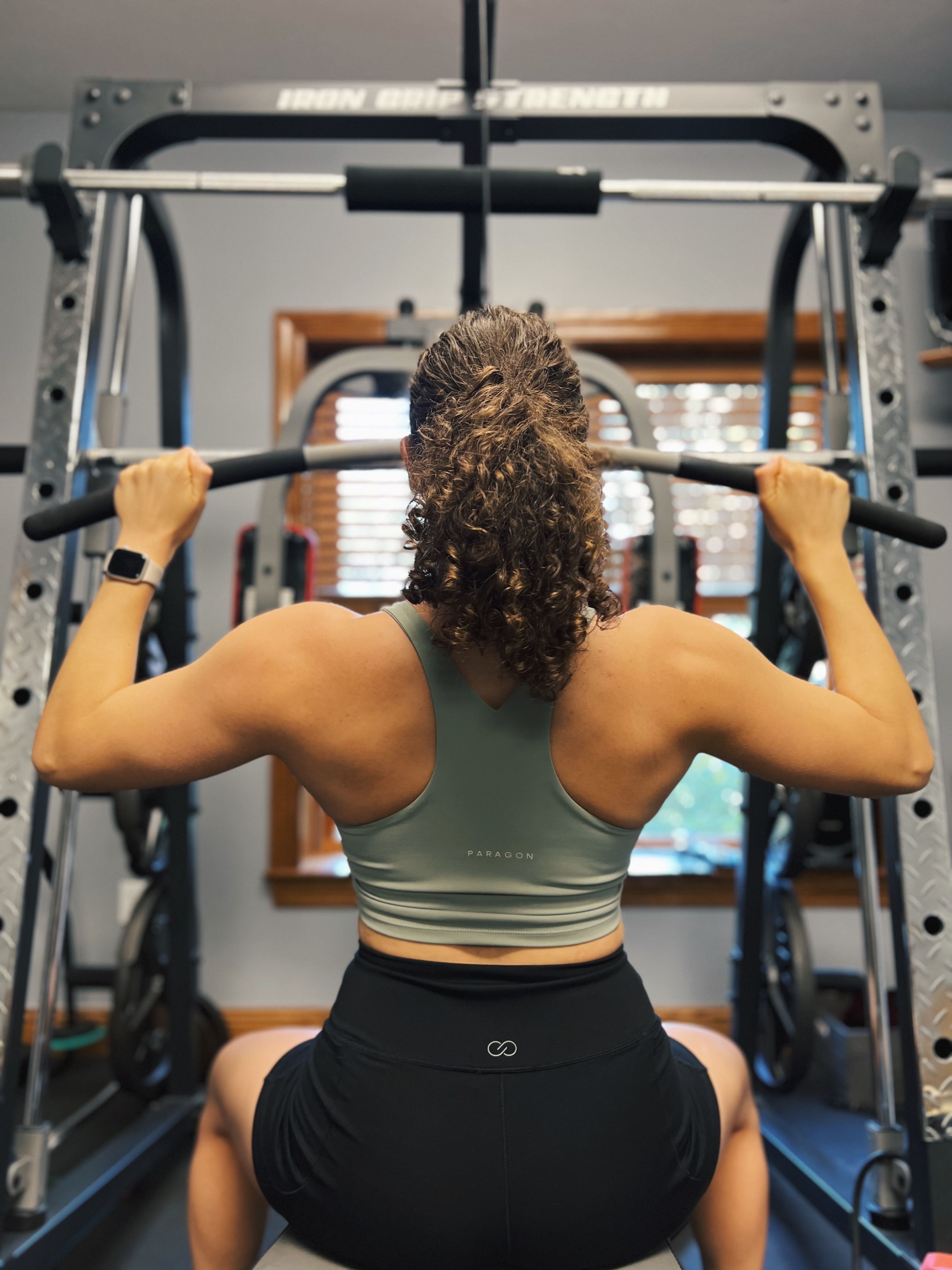 Fitness trainer performing lat pulldown exercise.
